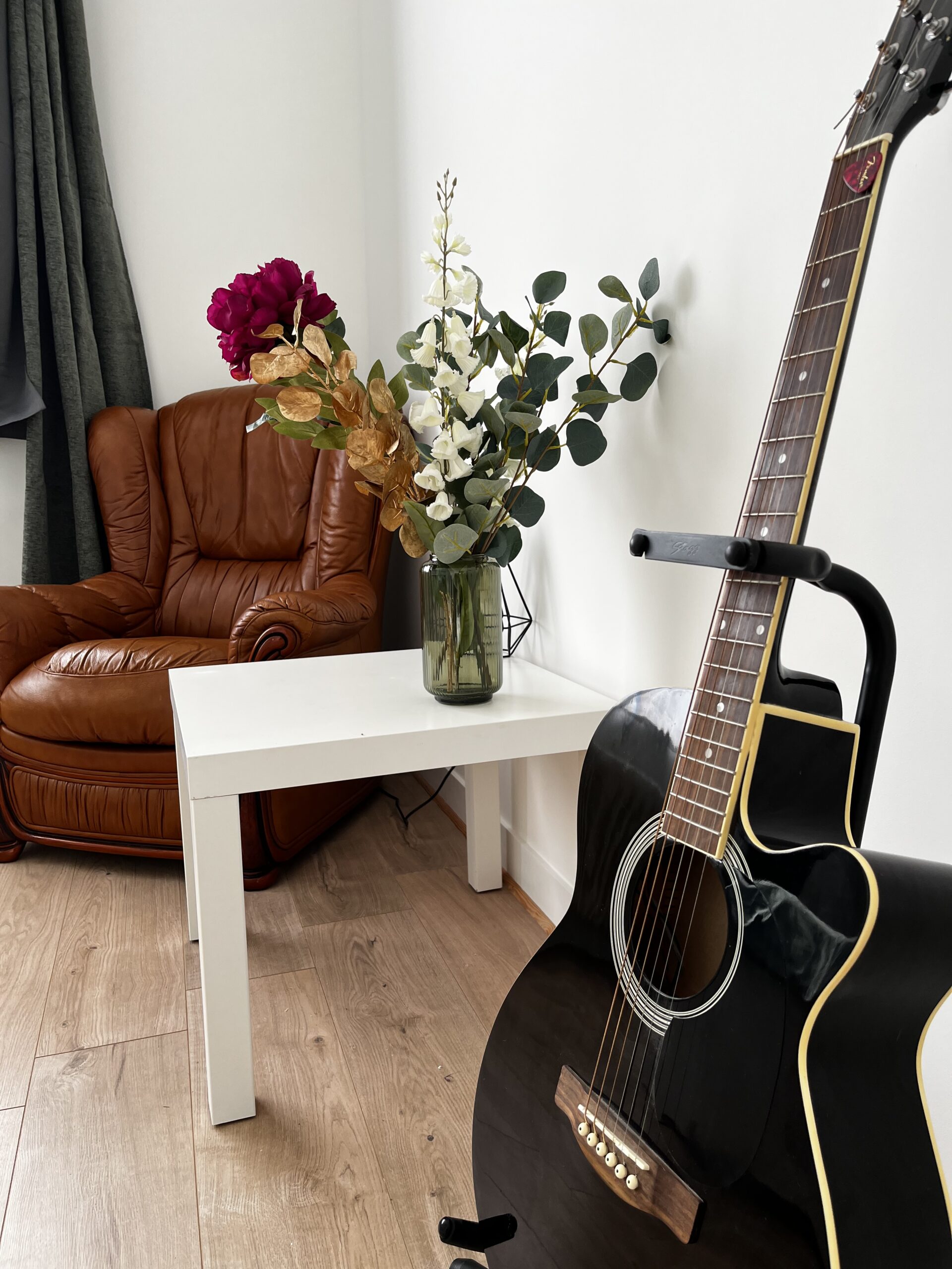 La chambre champêtre comporte également un grand placard avec penderie, un fauteuil, une table basse et une guitare folk.